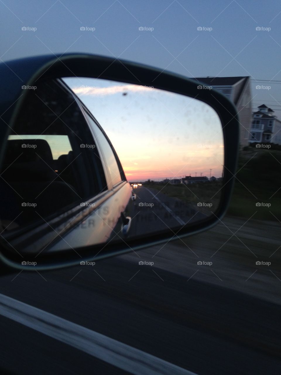 Sunset reflected in the rear view mirror of a car