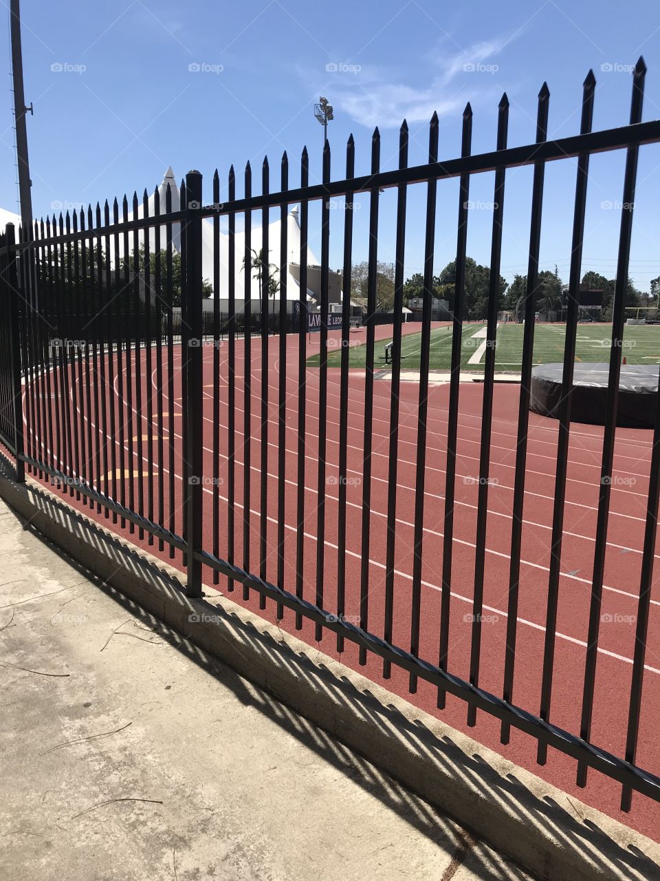 Rubber running outdoor track behind black fence