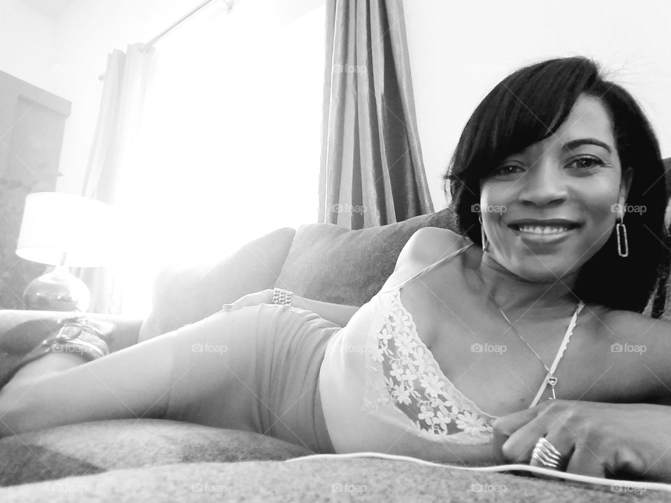 Happy african woman lying on sofa at home