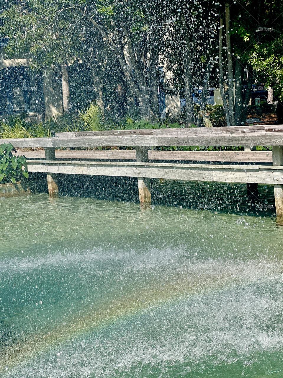 Fountain and water feature in city park on a sunny day. The water spray adds a rainbow to the urban environment.