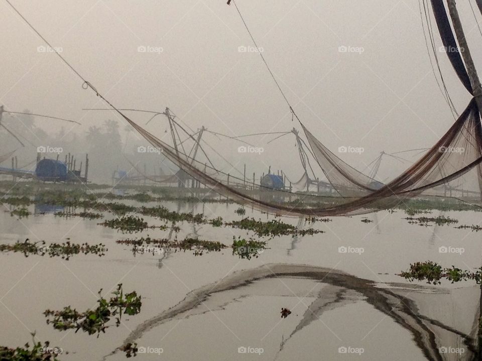 Fishing nets & it’s reflections lay still against the misty morning 