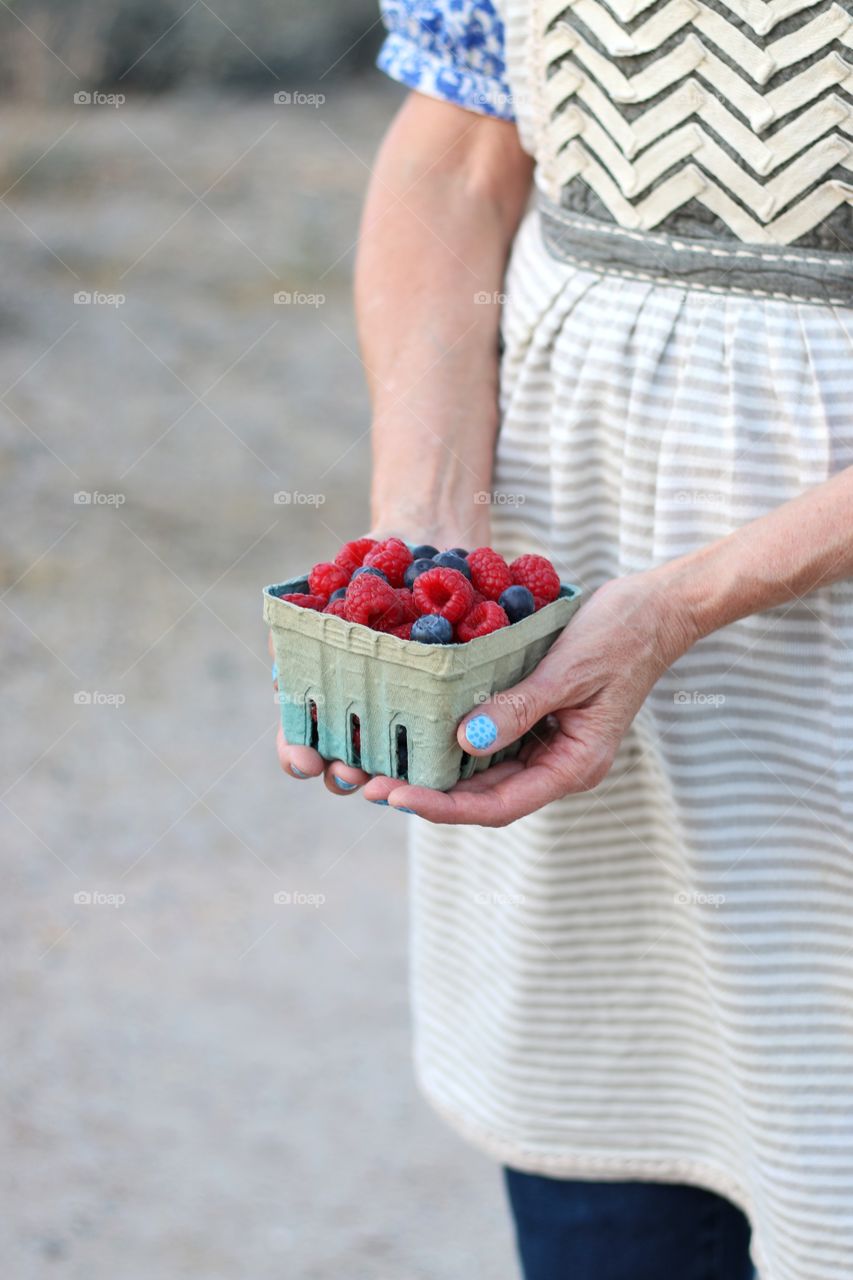 Woman holding raspberries and blueberries 