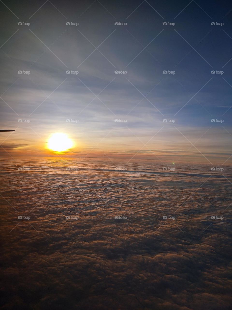 a beautiful heavenly sunset above the clouds from inside a plane..