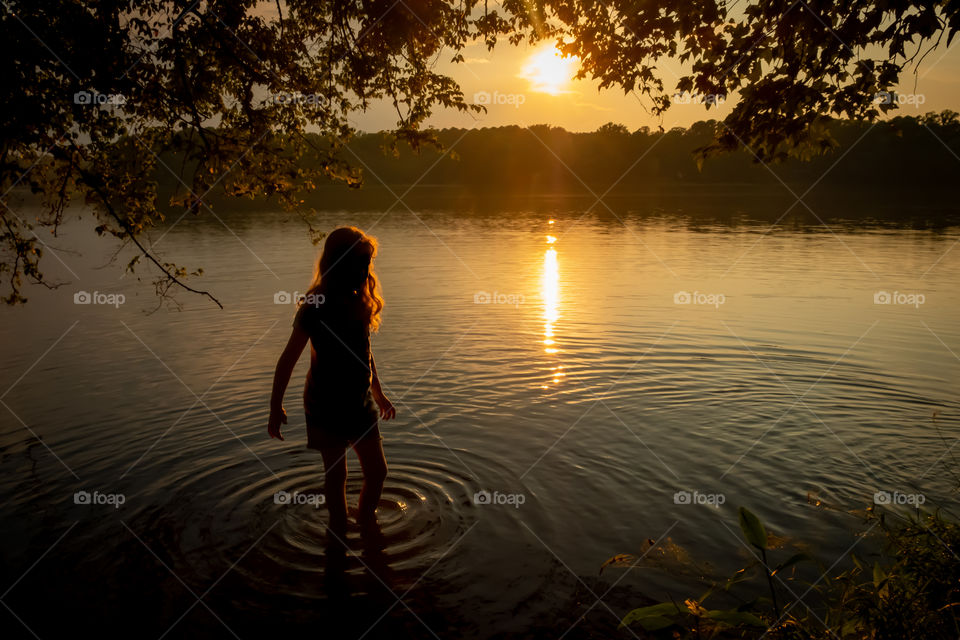 A young girl basks in the day’s waning golden light, as her feet explore the textures the lake has to offer. Lake Benson, North Carolina. 