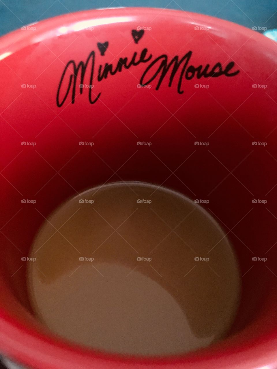 A close up of the inside of a red, Disney coffee mug. With Minnie Mouse’s signature on it 