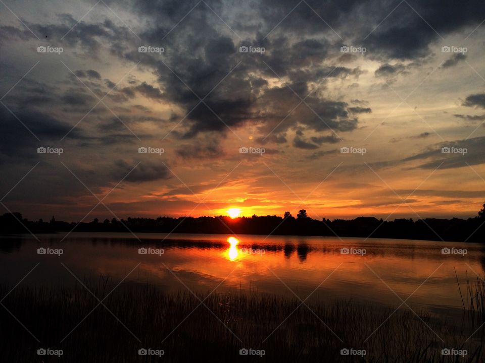 Beautiful, cloudy sunset by the lake In polish countryside