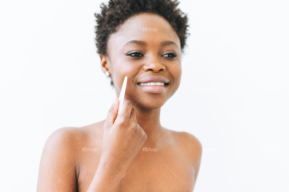 Young black woman girl does facial massage by guasha stone on white background 