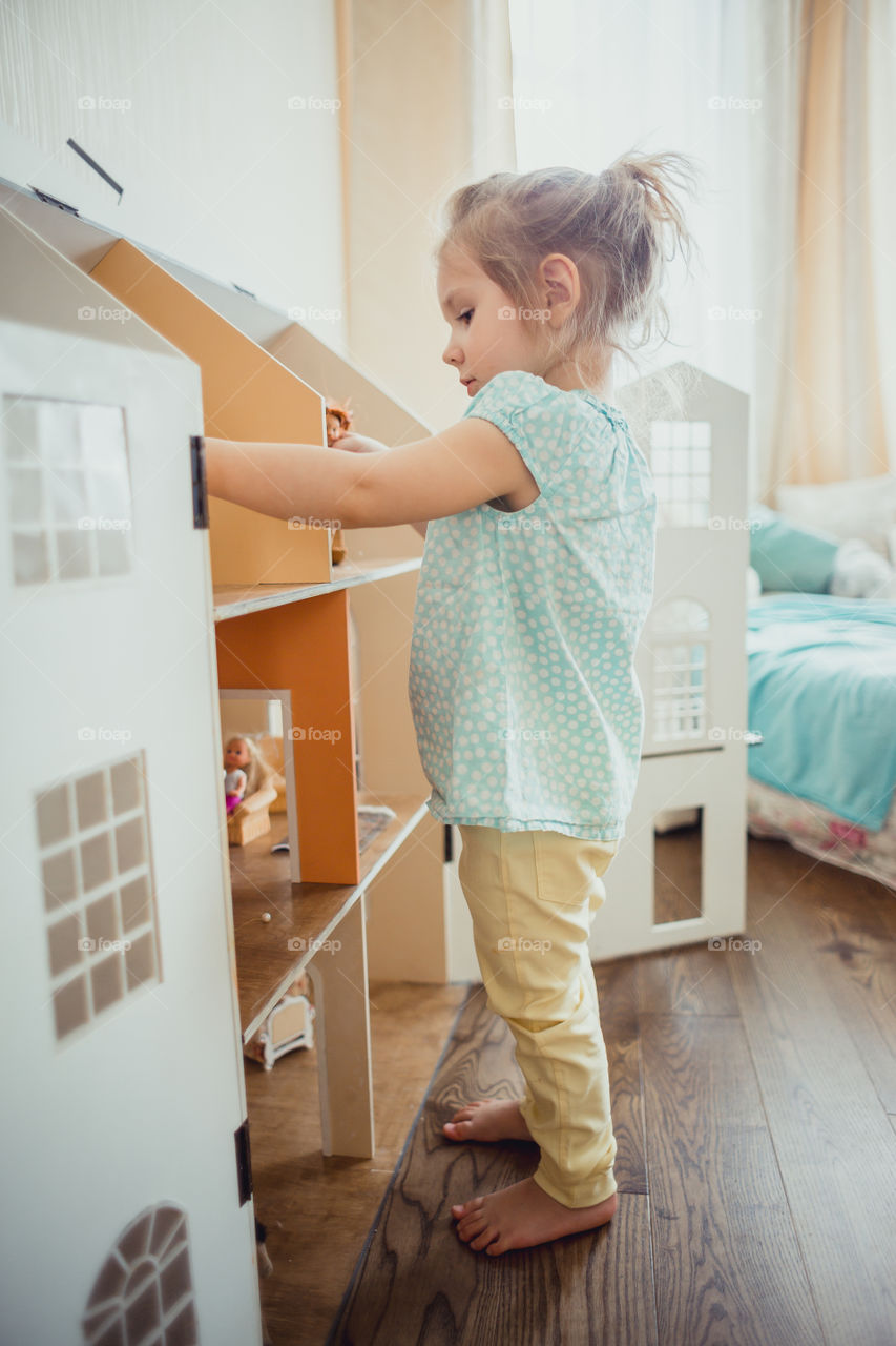 Little girl playing with dollhouse 