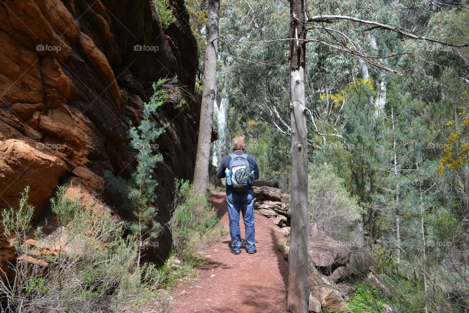 Man in backpack walking along trail in the Flinders Ranges of south Australia's outback