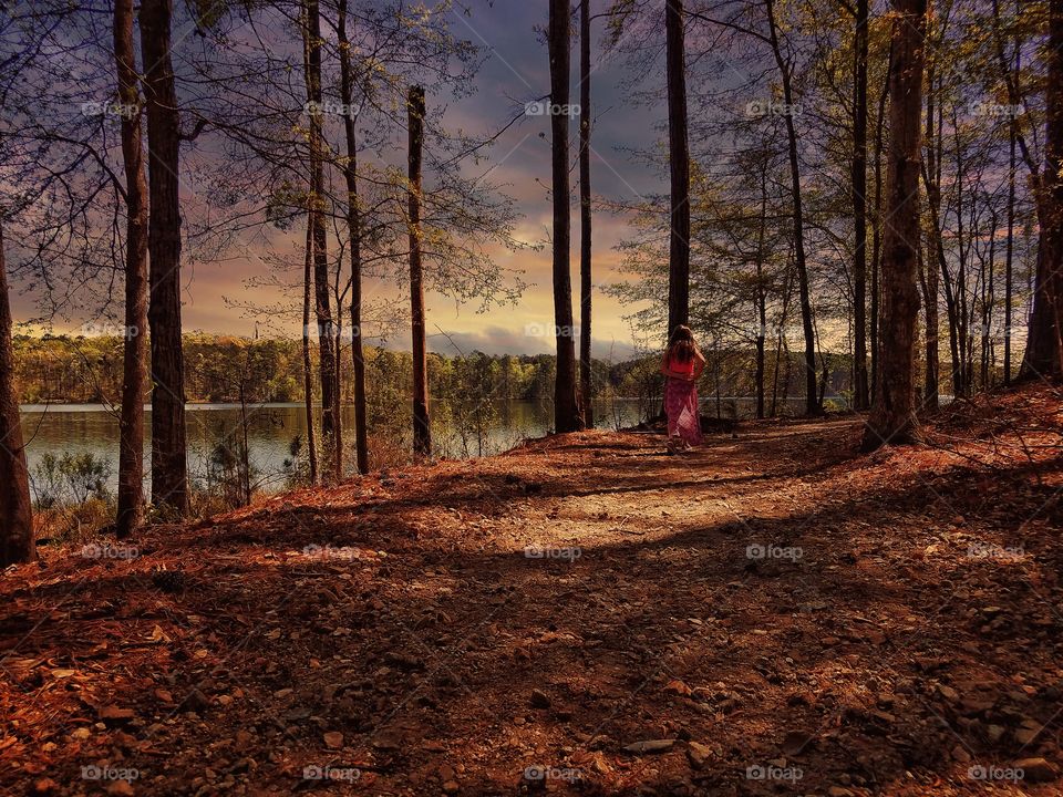 Girl walking in the sunset on a trail at the lake