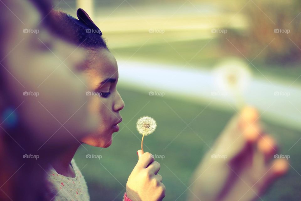 MAKE A WISH. Sisters enjoying their innocence, making a wish in the spring.