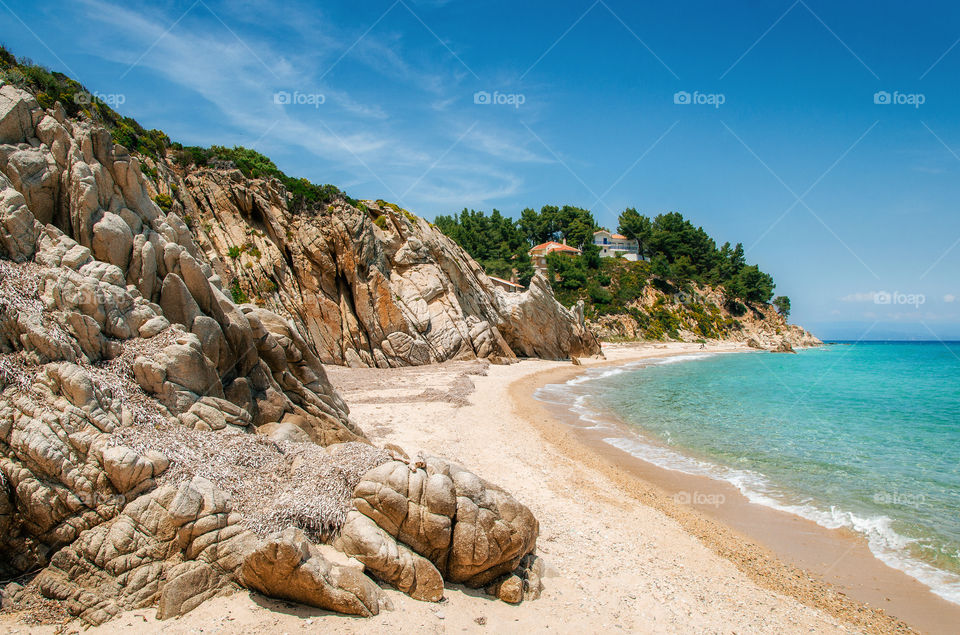 Hidden wild beach with stones and sand in Vourvourou, Halkidiki, Greece