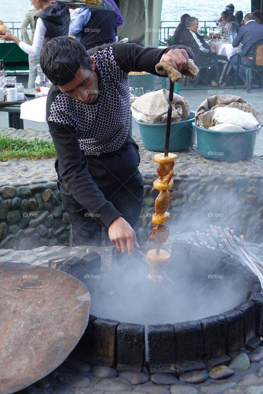 Asian man cooking skewer meat at barbecue