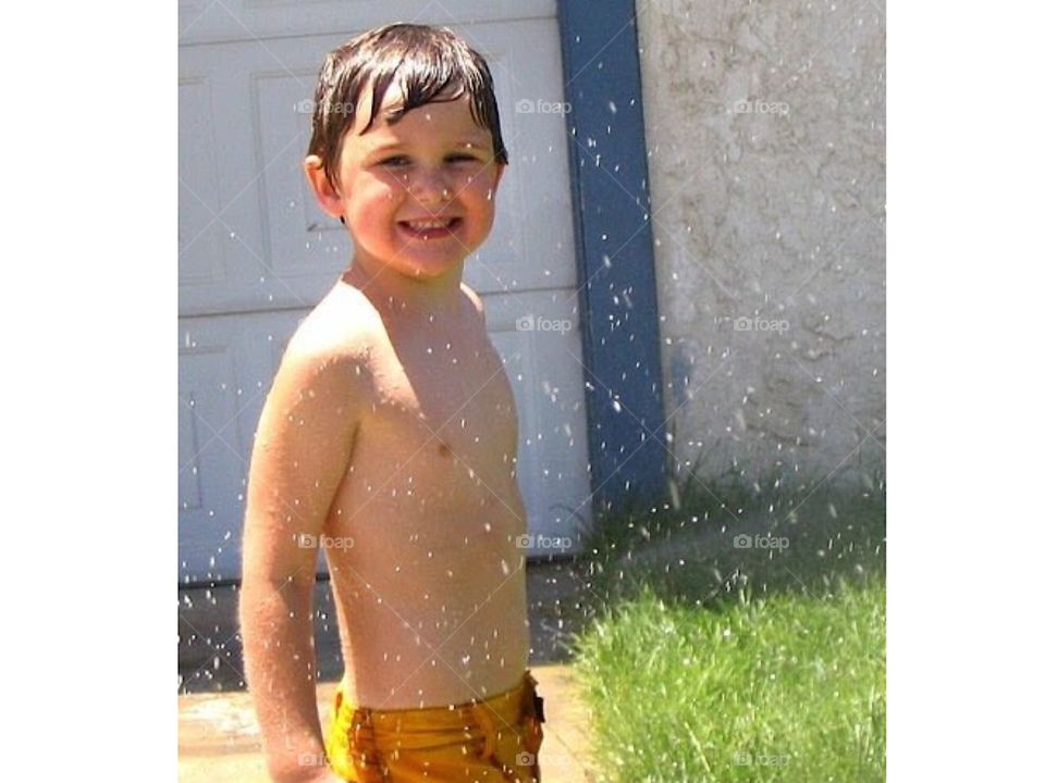 Little boy playing in the water outside.