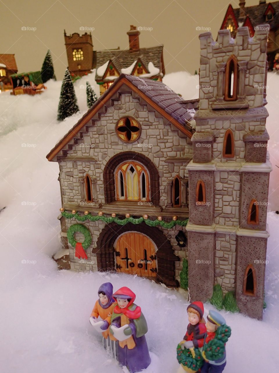 Figurines caroling in front of a church in a Christmas village display. 