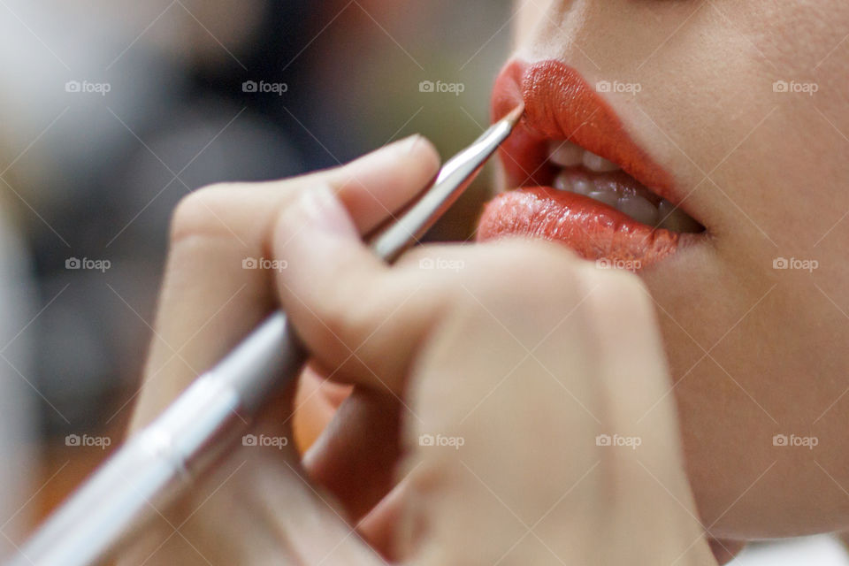 Girl paints lips with lipstick