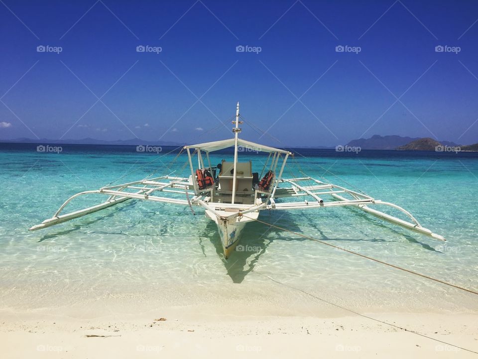 Pristine beach in the Philippines with a boat and clear water. 