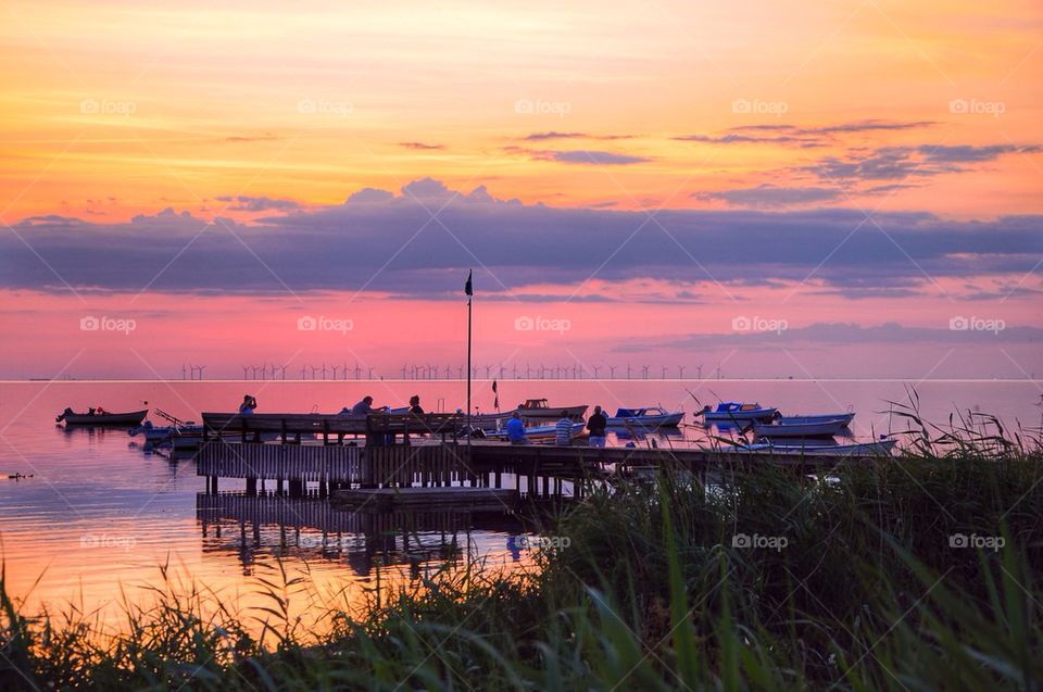 Boats moored near jetty at sunset