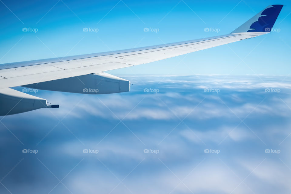 Plane flying high above fast-moving clouds pattern.