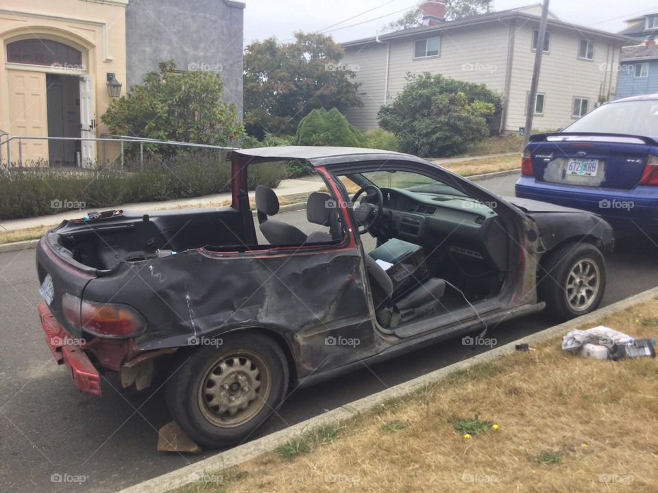 A completely destroyed and burned out car with doors and trunk gone