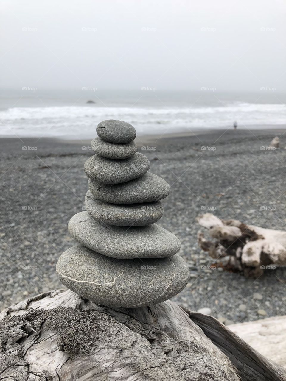 Rocks stacked by the ocean with sea wood in background / zen / peace