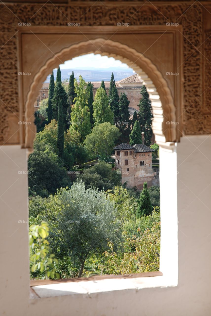 The gardens of the Alhambra through a small arch window