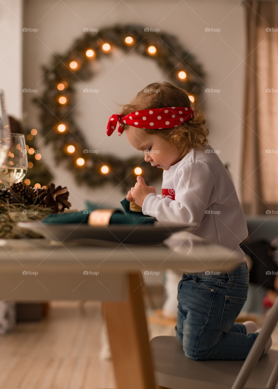 little girl sits at a decorated Christmas table