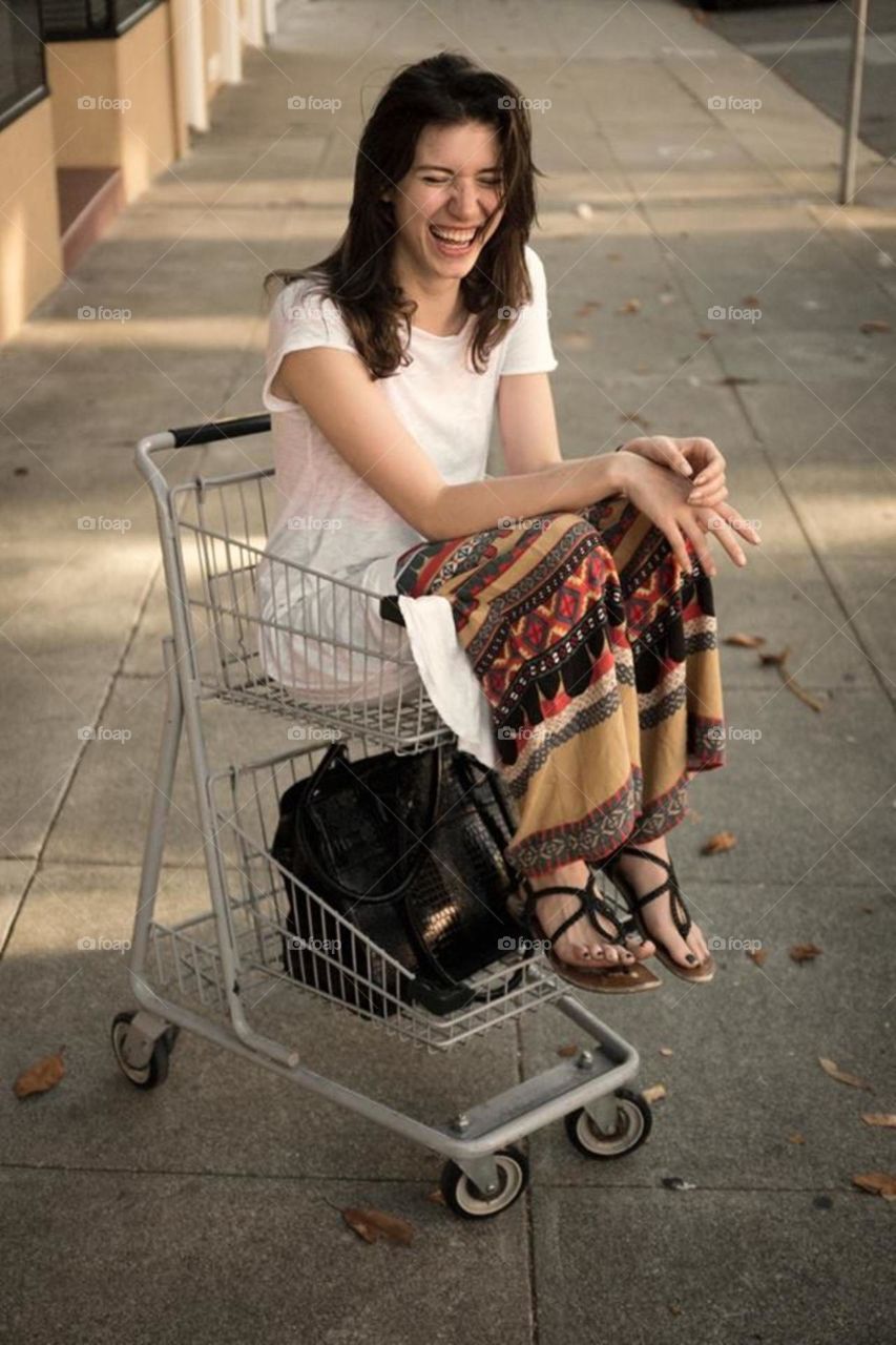 Cute girl laughing in shopping cart funny