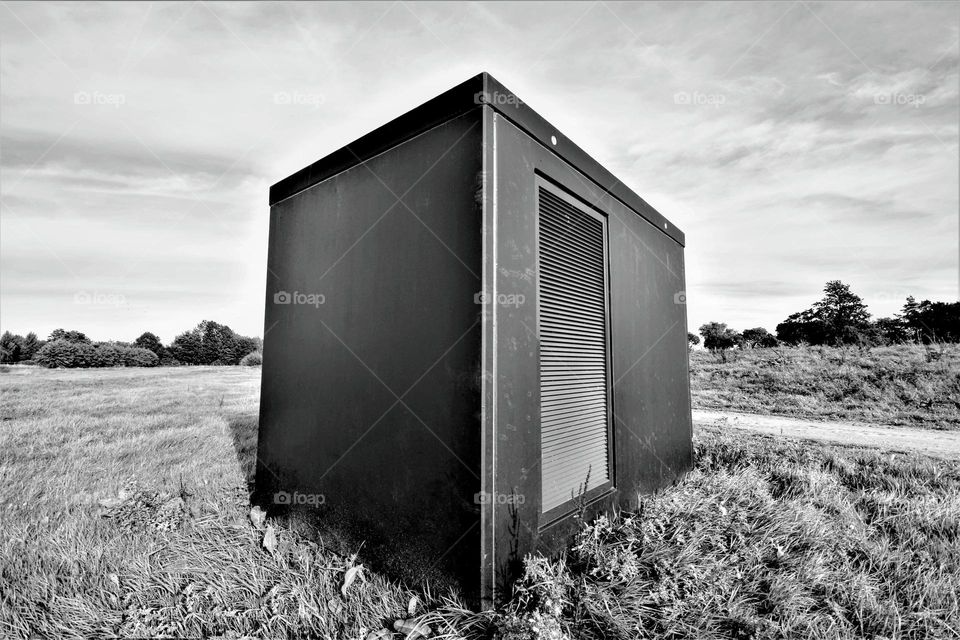 minimalistic black and white wide angle picture with electric transformer house in an empty field