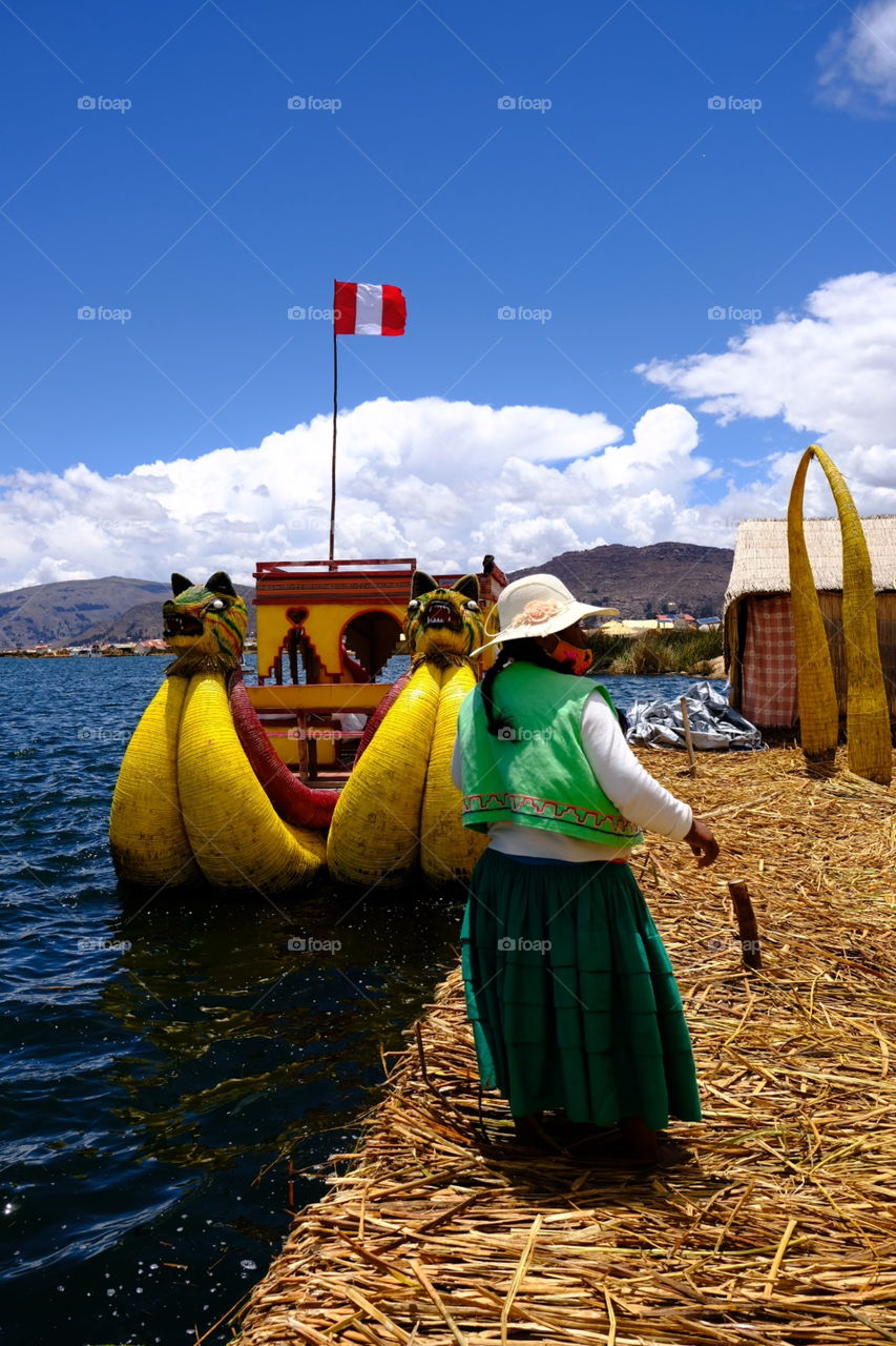 Uros inhabitant near a tourist boat