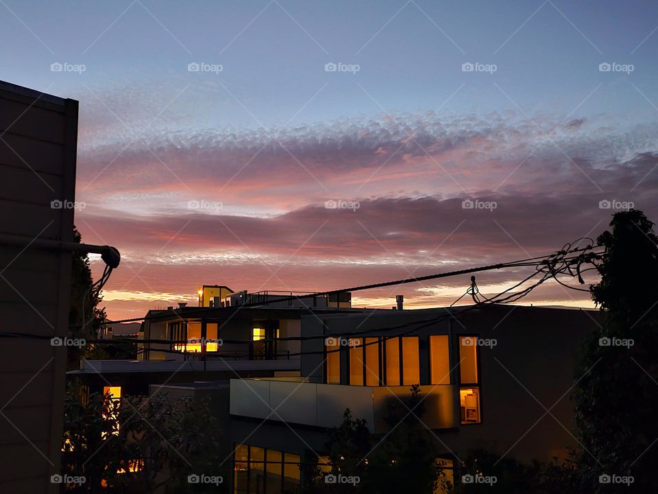 dusk in San Francisco California looking between the rows of homes with the glow of the lights and the beautiful soft clouds as night falls