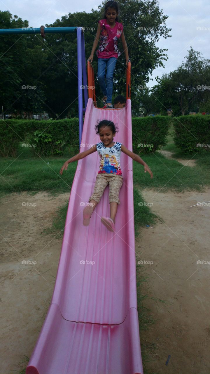 Asian girls enjoying on slide in park