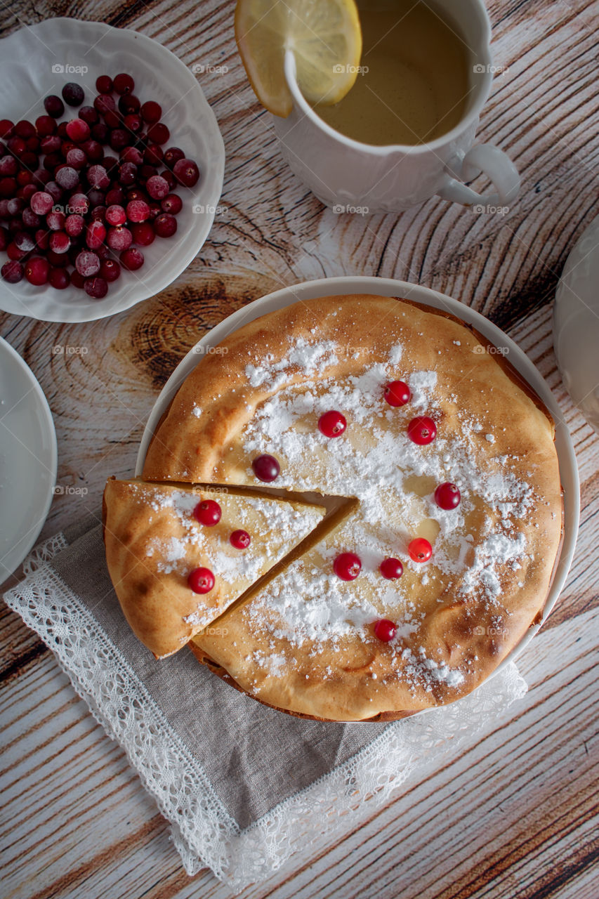 Cheesecake with cranberries and sugar on wooden background