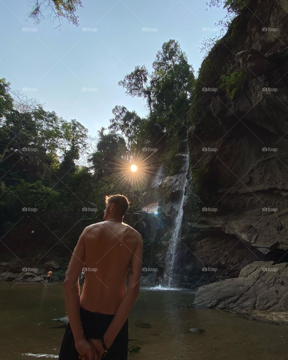 Waterfall with sun piercing through the jungle canopy 