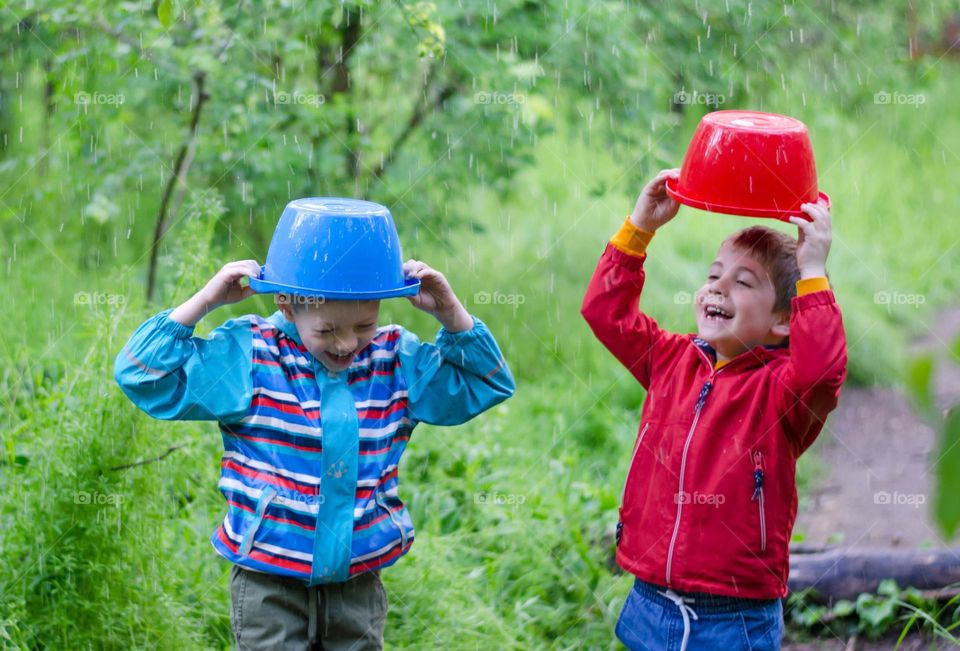 Children Playing in Rainy Spring Day with Buckets on Their Heads