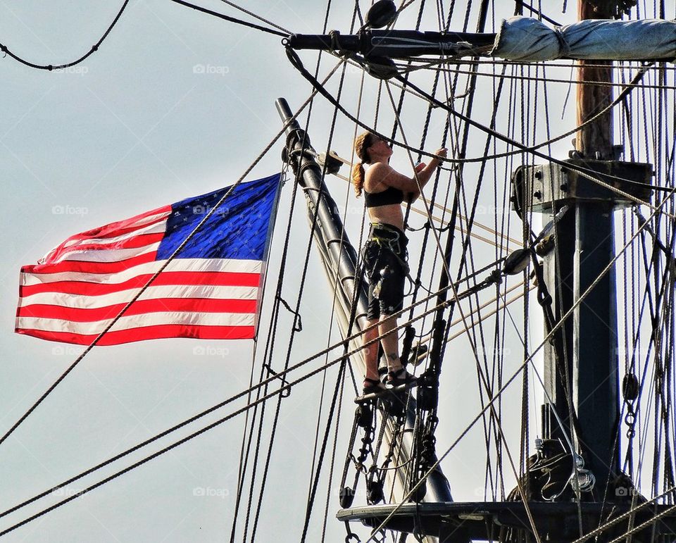 Female sailor climbing rigging of a sailing ship