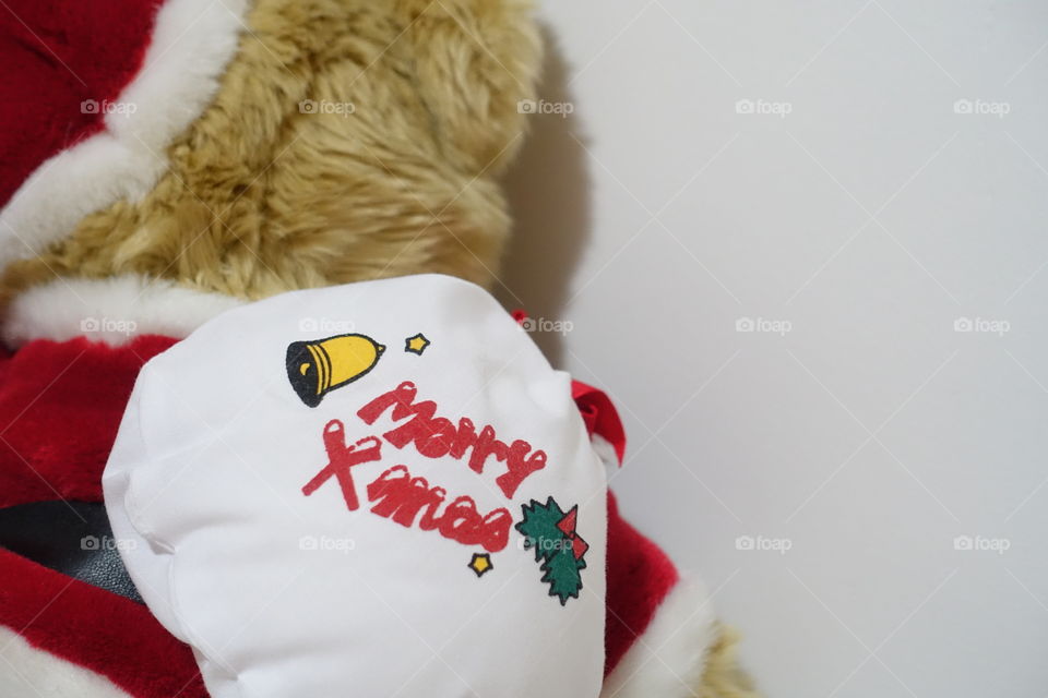 Teddy bear wearing in Santa costume brings presents and says “ Merry Xmas”. 