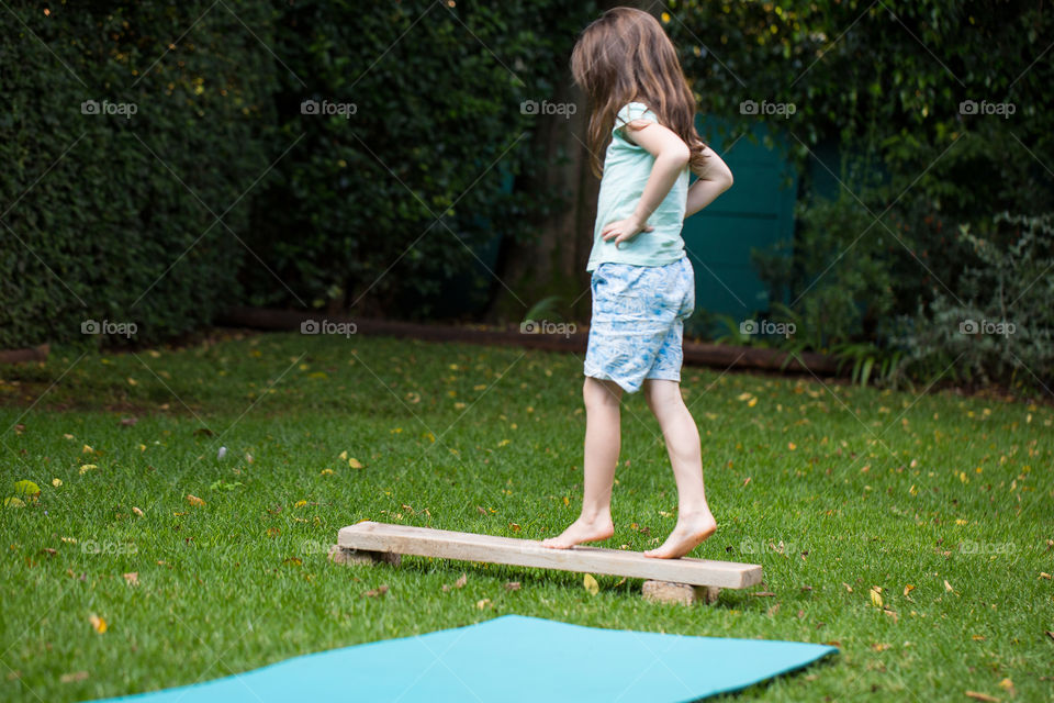 Stay at home - I created an outdoor obstacle course to encourage play and exercise. Image of girl balancing on wood. Other activities included jumping rolling crawling and ball play.