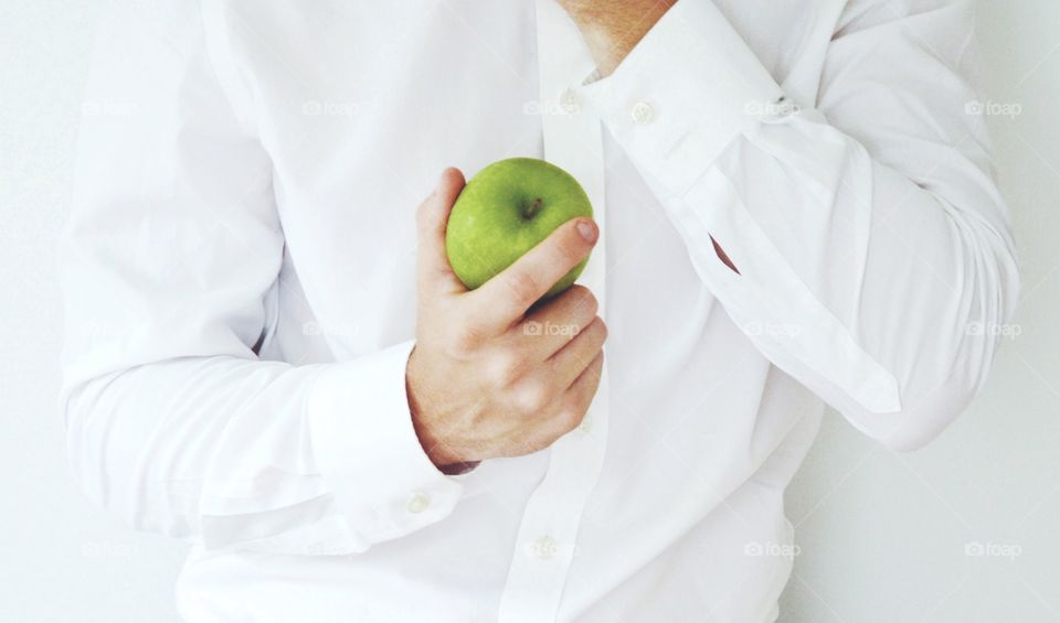 Photo of a businessman holding a green apple and wearing a white shirt