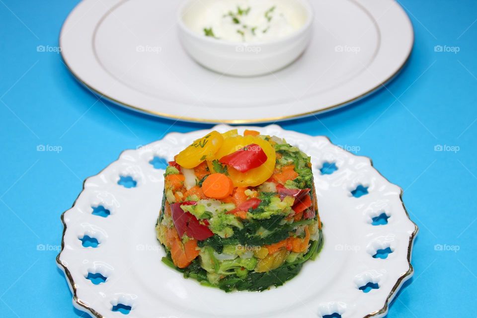 Boiled vegetables on white plate: carrots, cauliflower, broccoli and pepper.  Angle view of food