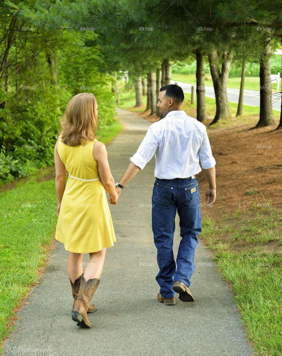 Rear view of couple walking together on path at park