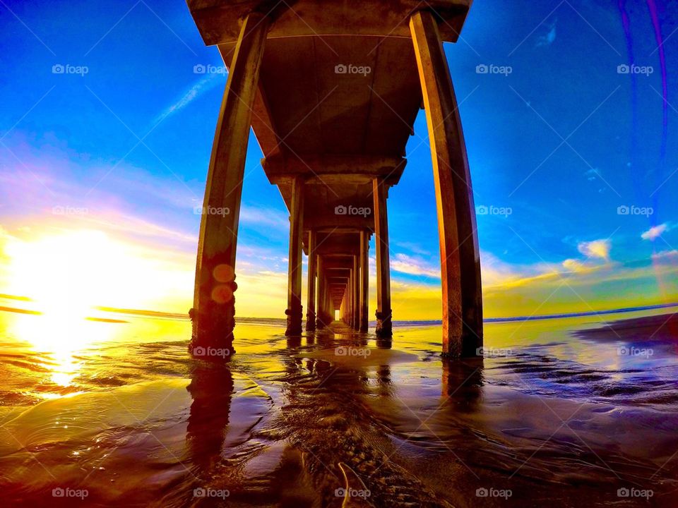 Low angle view of pier in sea at sunset