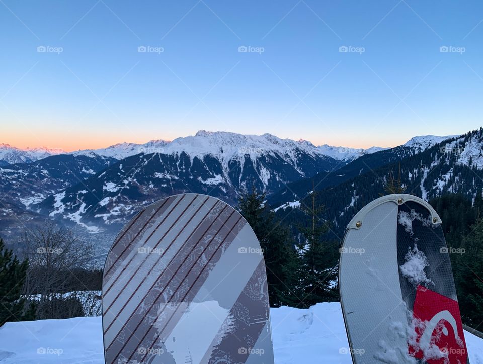 beautiful red sunset in the mountains and two snowboards in the foreground