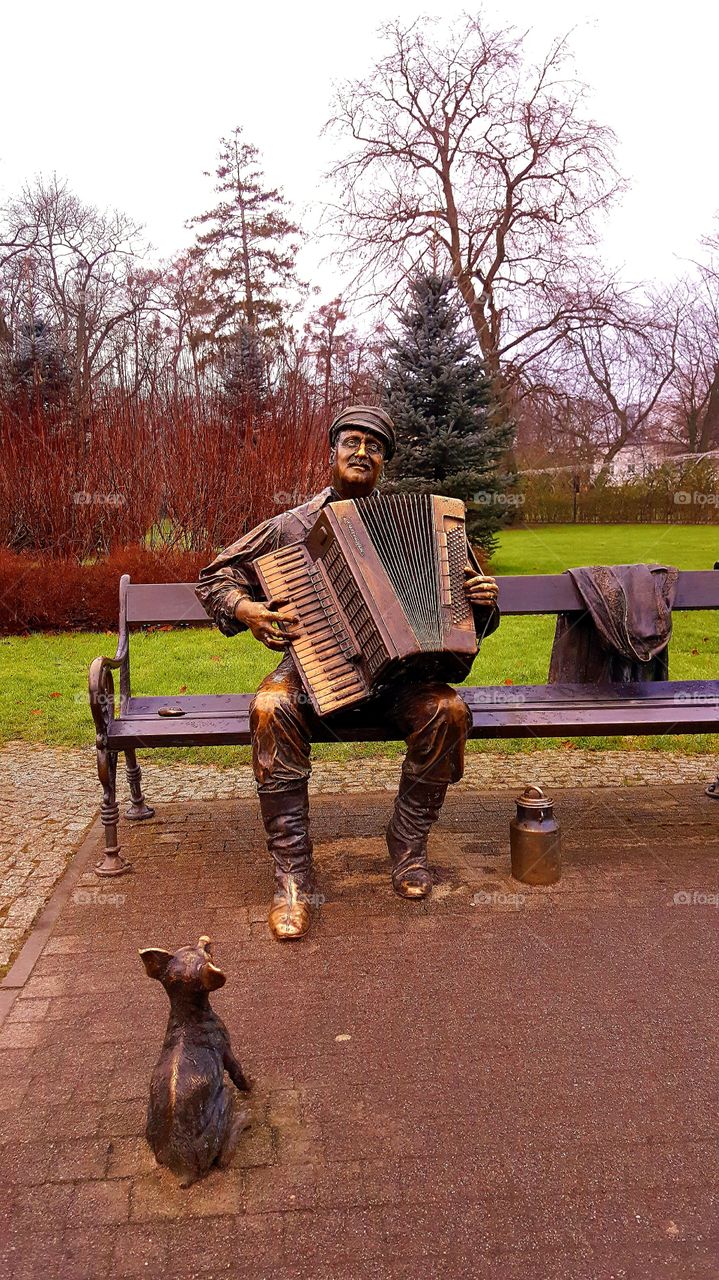 A musician's statue on a park bench.