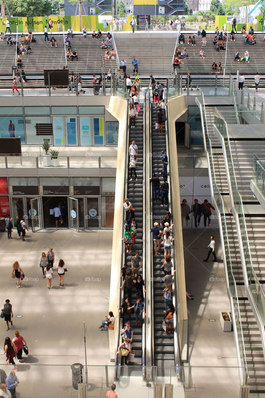 a view of people on escalators in an open air shopping and business center in Paris.