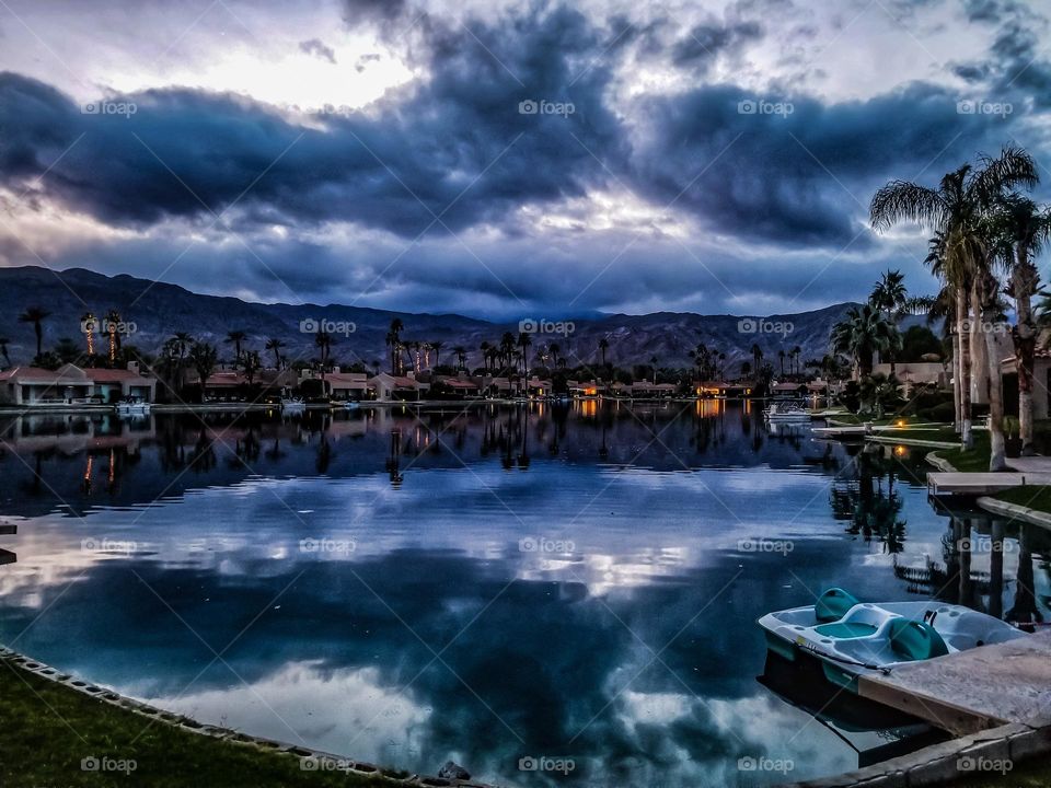 On the cusp of a stormy night in rancho mirage California with the clouds reflecting on the lake in an ominous way 