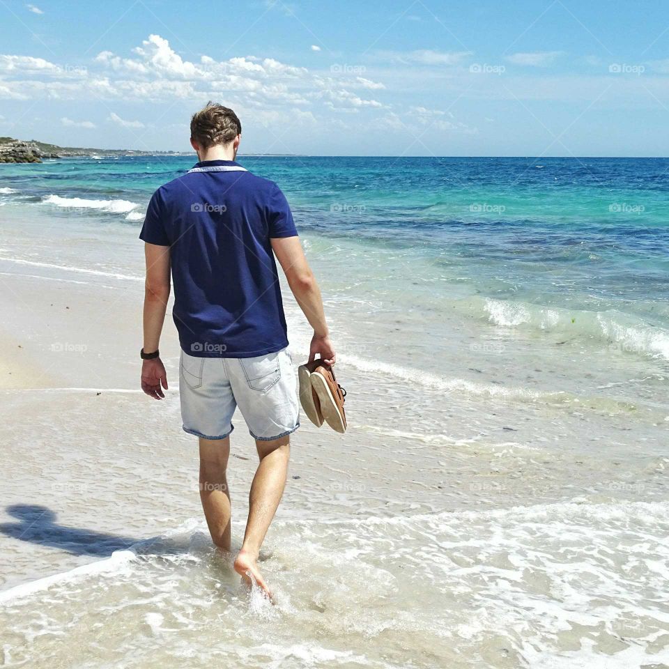 Man walking alongside a beach