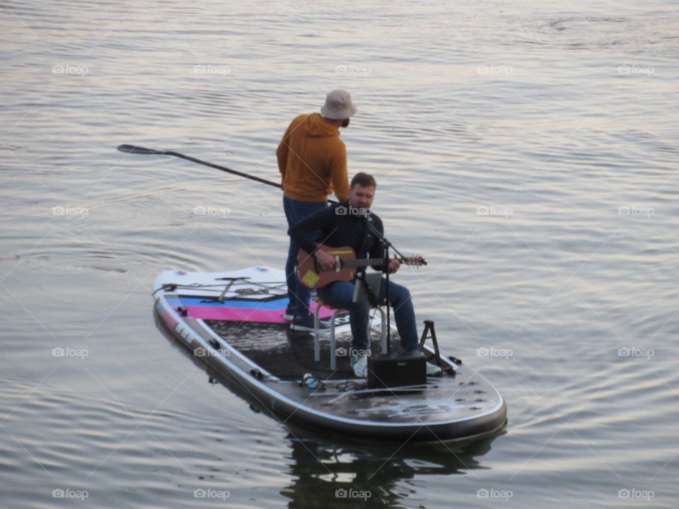 concert of a musician on the water for people in boats, evening, river, Voronezh city, Russia, autumn, warm weather
