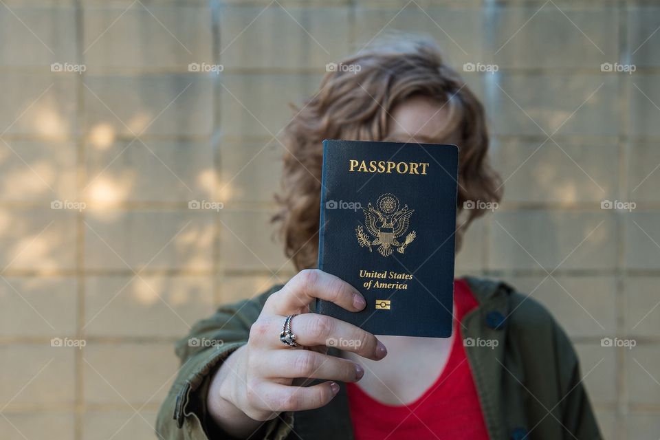 Girl holding US passport extended towards camera view