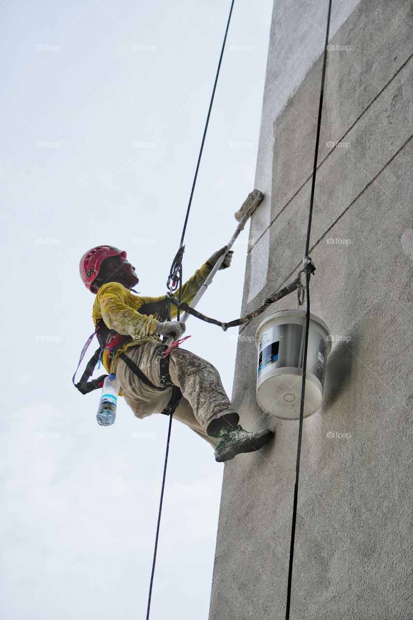 Worker abseiling down the side of a tower block in Kuala Lumpur Malaysia